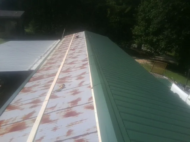 Old rusted panels beside newly installed green metal roofing — Wind Damage Roof Repair by Roofing Brothers in Peach Bottom