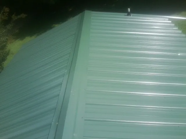 New green metal panels meeting at the ridge of a roof — Flat Roof Repair work by our crew in Peach Bottom