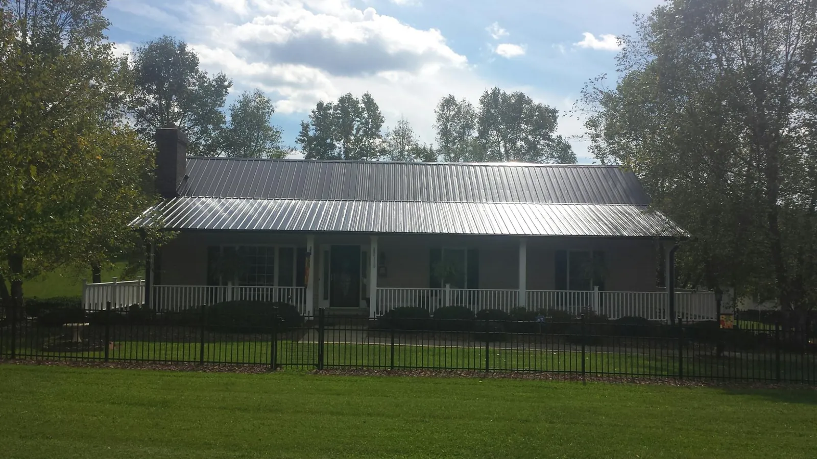 Gray metal roof on a brick ranch with a full width front porch — Gutter Guard Installation work by our crew in Peach Bottom