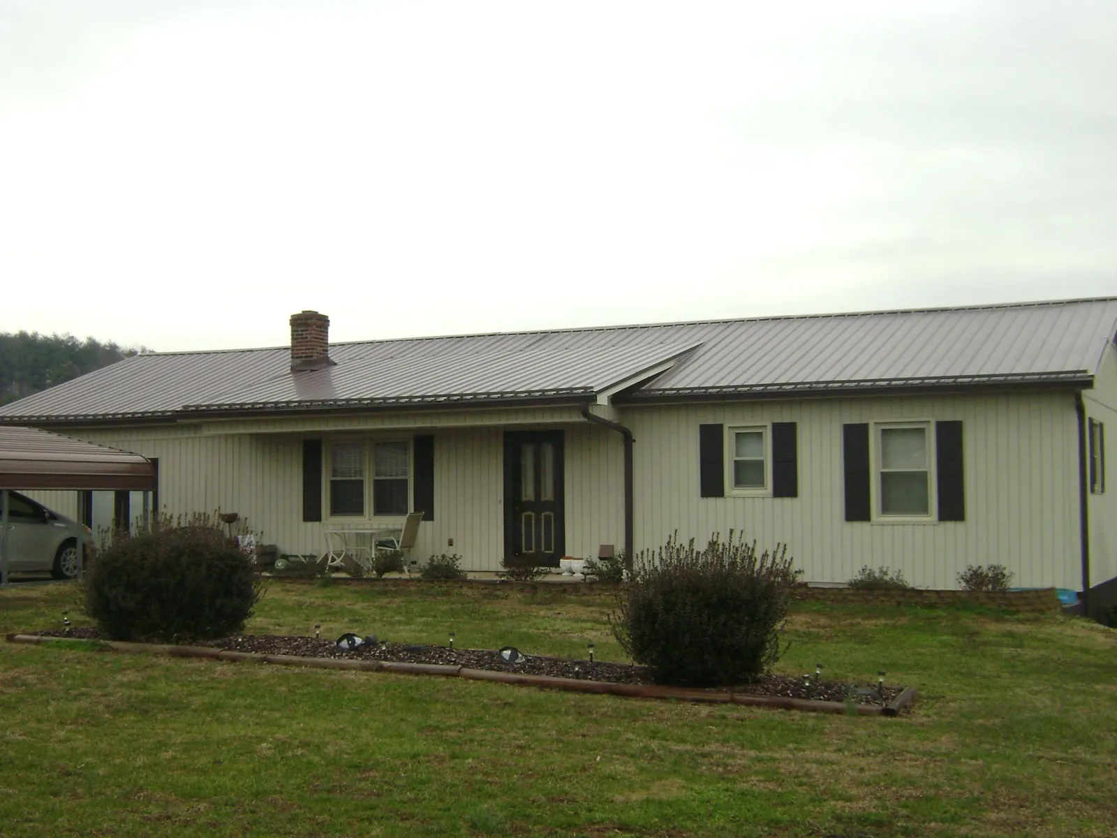 Brown metal roof on a cream sided ranch home with a brick chimney in Peach Bottom