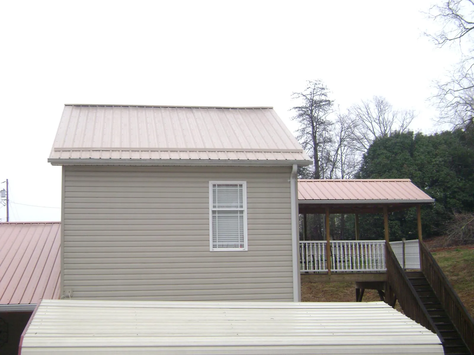 Tan metal roofs on a two story addition and attached porch, from a Roof Replacement job in Peach Bottom