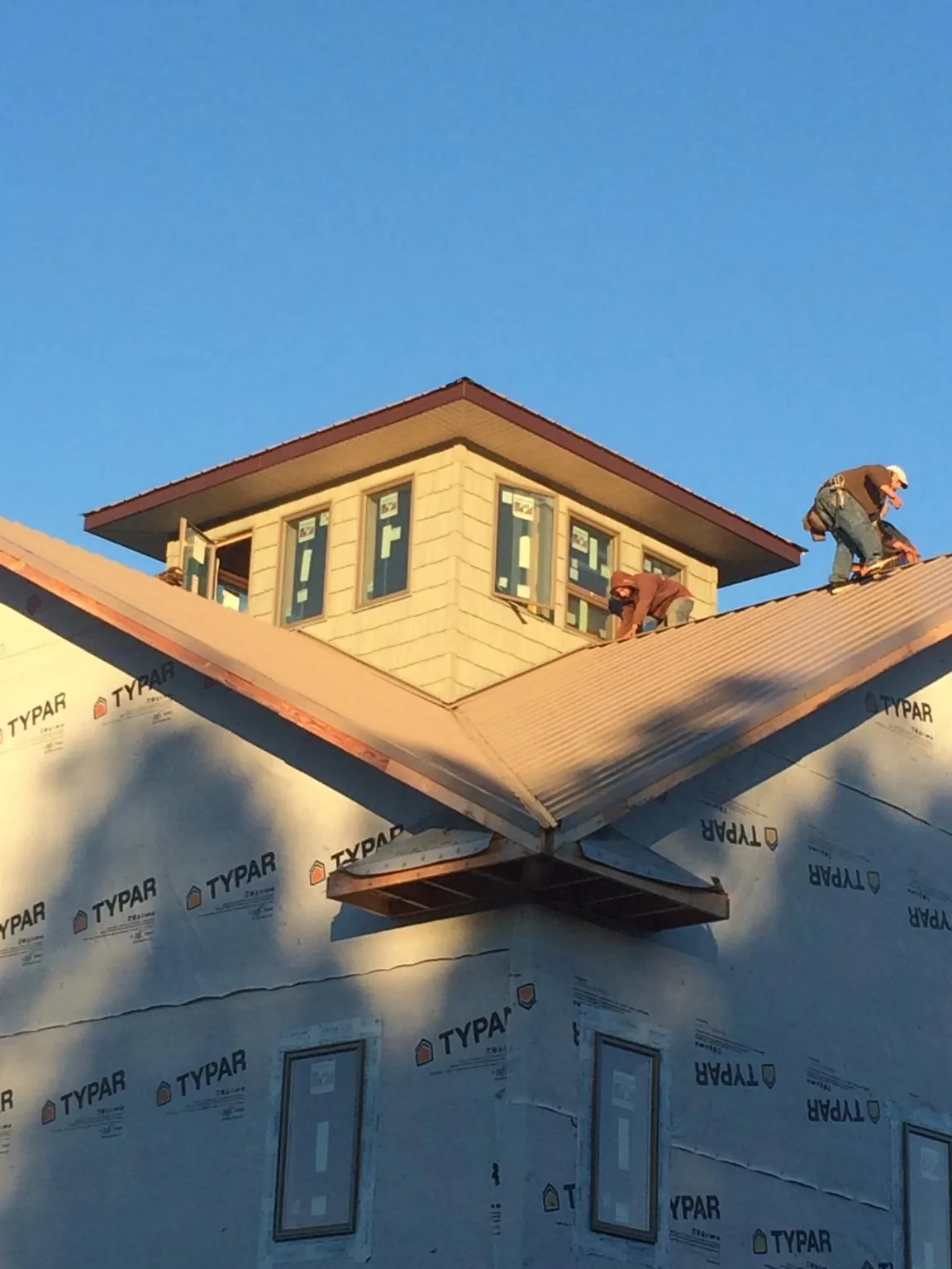 Roofers working around a rooftop cupola on a new metal roof at sunset — Roof Waterproofing in Peach Bottom by Roofing Brothers